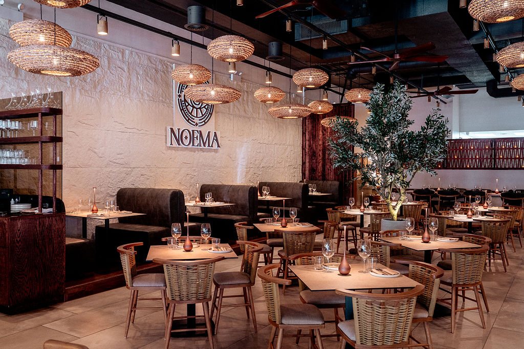 Noema's dining room with woven pendant lights and the Noema emblem on the wall