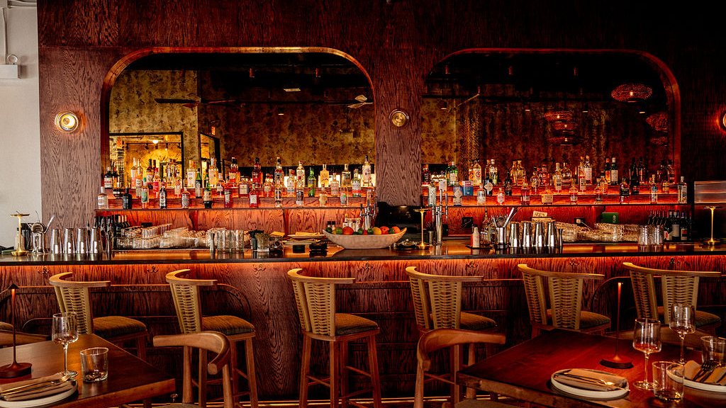 The bar at Noema with warm lighting and backlit shelves